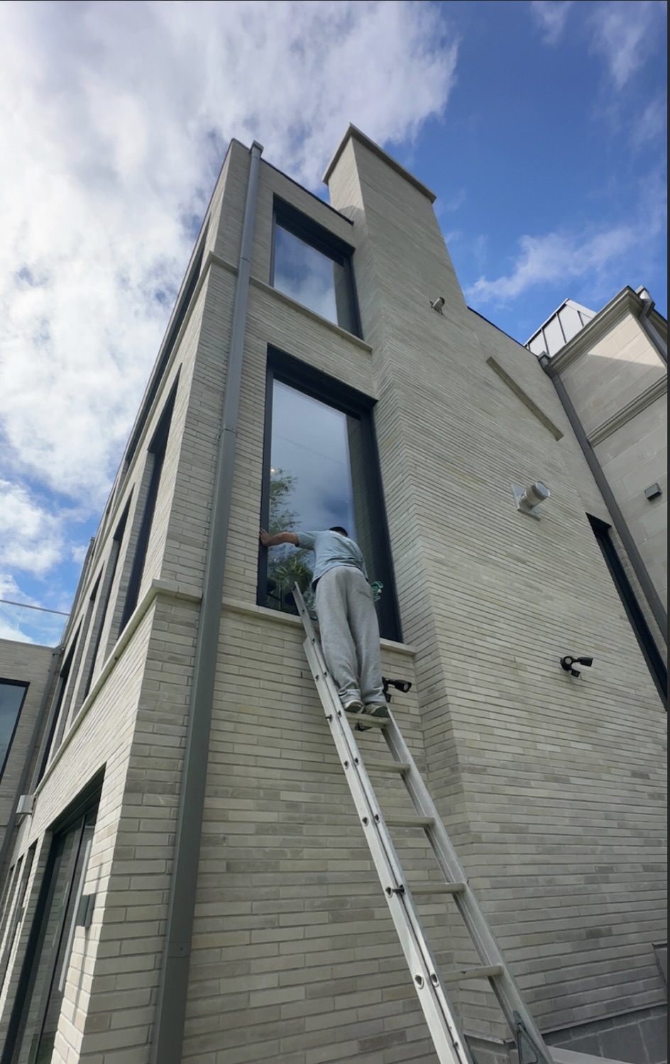 On a ladder cleaning a tall window