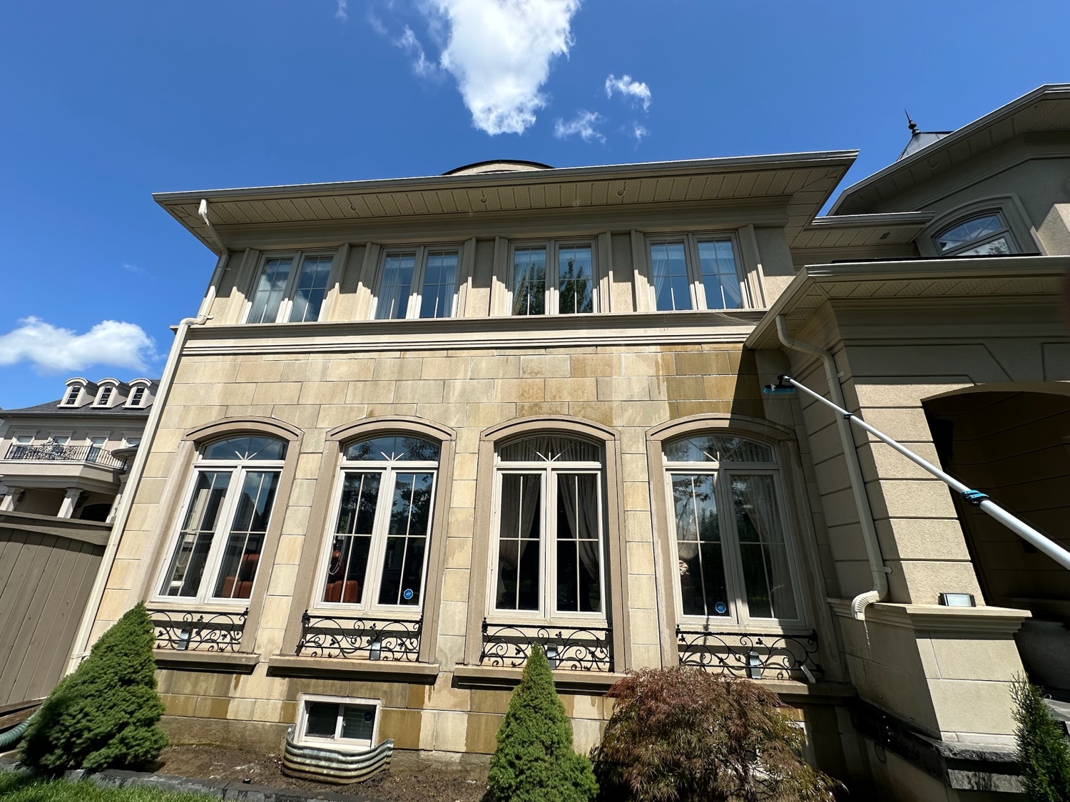 Cleaning arched windows on a stone mansion